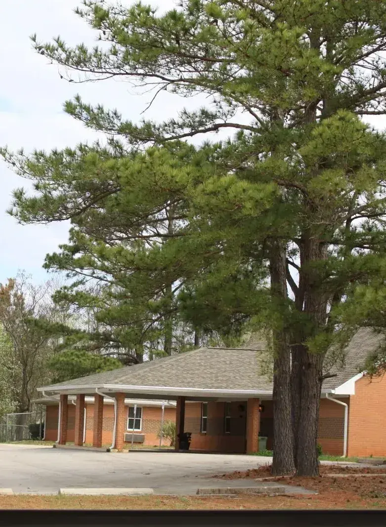 The brick residential facility of The Wave of Columbia, surrounded by tall pine trees in Winnsboro, South Carolina