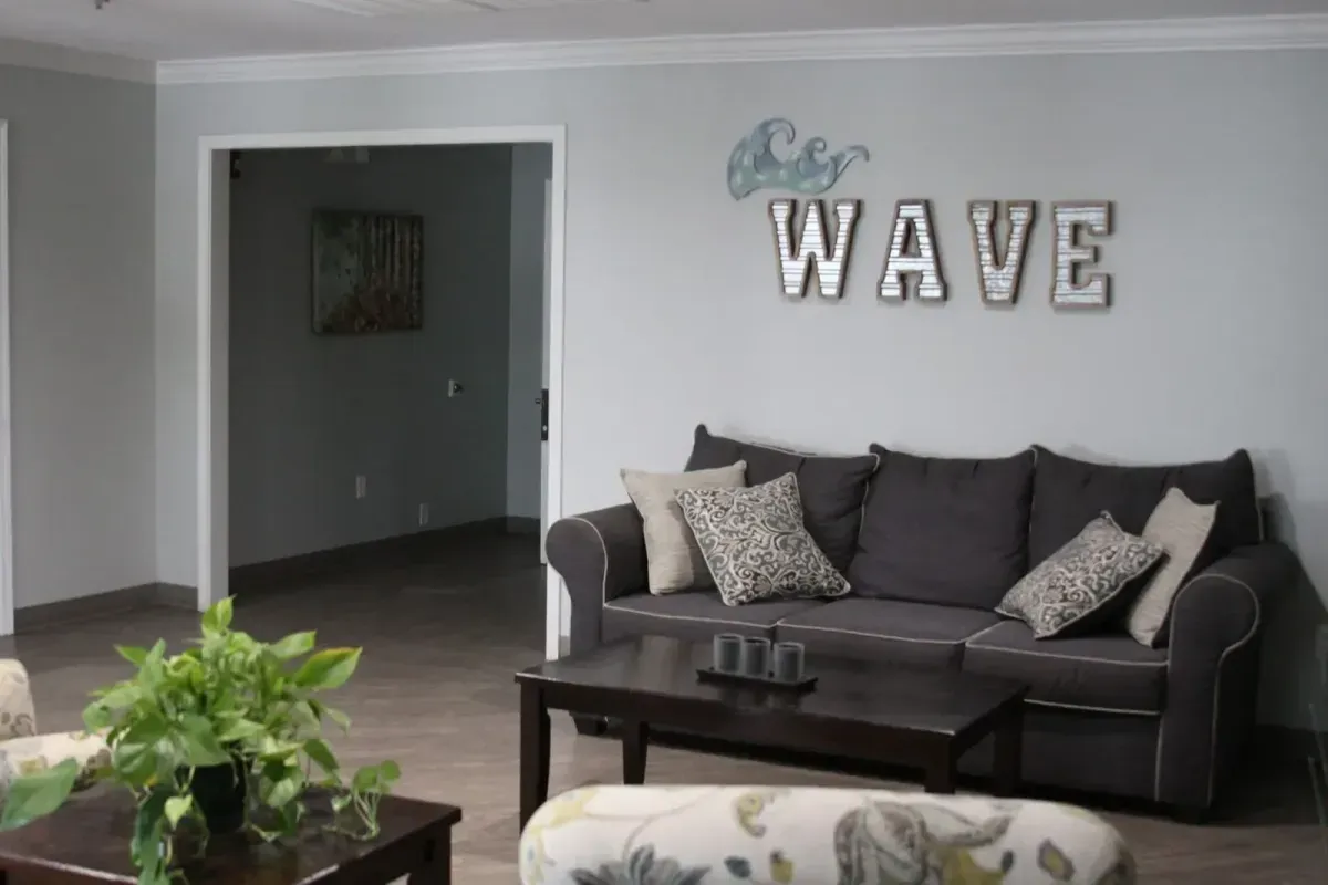 The cozy common room at The Wave of Columbia, with comfortable seating and a WAVE sign on the wall