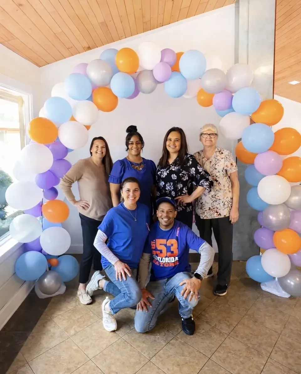The care team at The Wave of Columbia smiling together under a balloon arch
